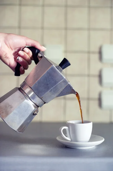 Mão perto derramando café expresso em uma xícara — Fotografia de Stock