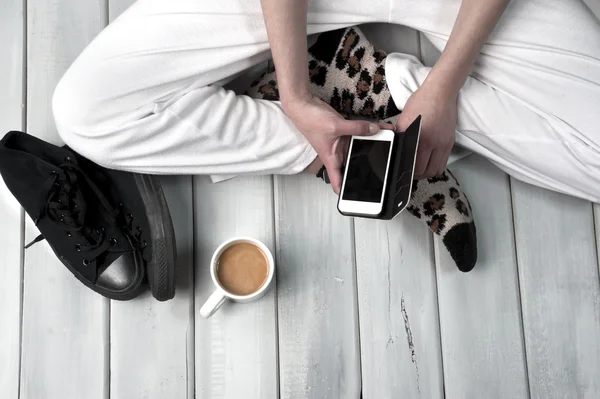 Femme assise sur le sol tenant un smartphone — Photo