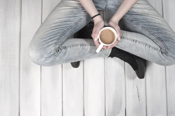Teenage girl sitting on floor holding a cup of coffee — Stock Photo, Image
