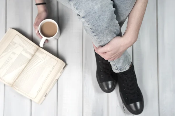 Teenage girl sitting on floor holding a cup of coffee — Stock Photo, Image