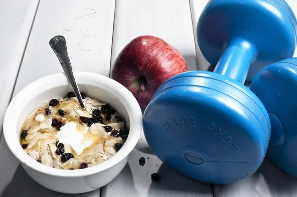 Dumbbells and red apple next to bowl with yogurt — Stock Photo, Image