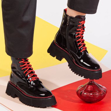 Siyah pantolonlu kadın bacakları ve orta topuklu siyah kısa ayakkabılar stüdyoda renkli bir arka plana karşı duruyor..