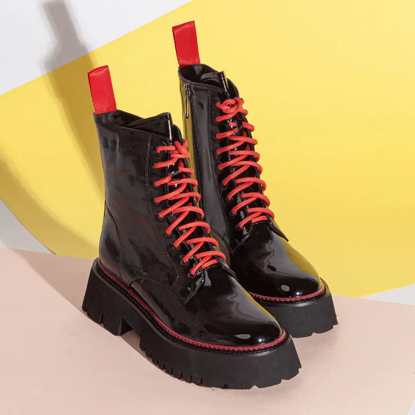 Woman\'s big balck shoes boots with red laces in studio.