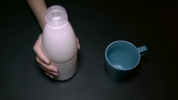 Kvinna som häller mjölk i en blå kopp — Stockvideo