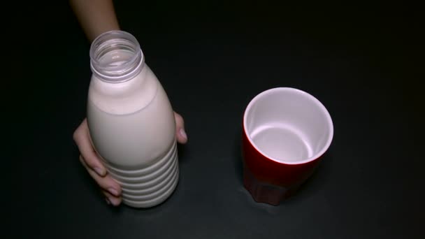 Vrouw giet de melk in een glas rood wit — Stockvideo