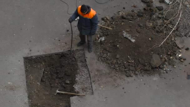El trabajo rompe terreno bajo el asfalto en el pozo — Vídeo de stock