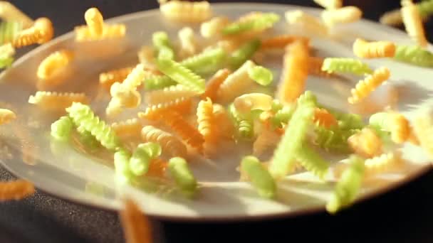 Çok renkli makarna çiğ beyaz bir tabak içinde dökülür — Stok video