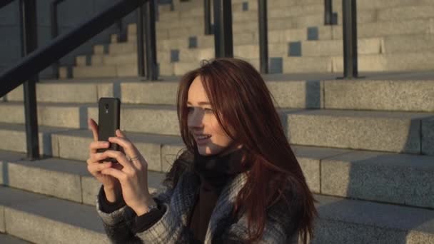 Chica sentada en los escalones con un teléfono — Vídeos de Stock