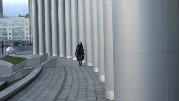 Meisje loopt langs de grote grijze kolommen, — Stockvideo