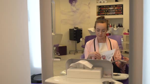 Mujer en silla de peluquero leyendo una revista — Vídeos de Stock