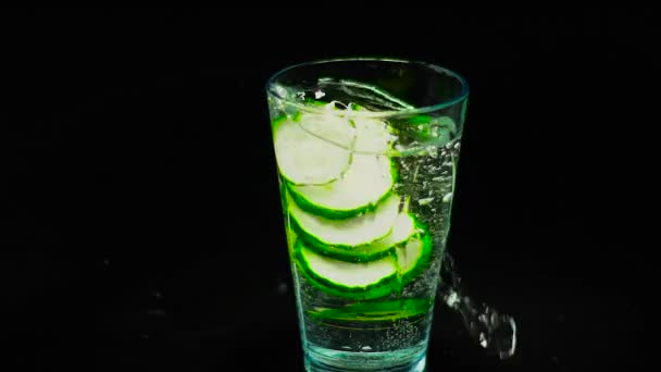 Concombre tombant dans un verre d'eau minérale — Video