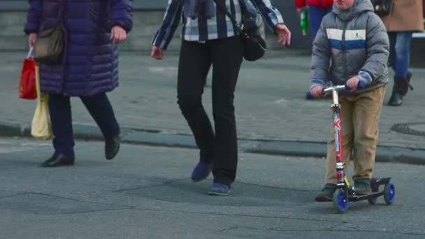 Мальчик на скутере едет через дорогу — стоковое видео