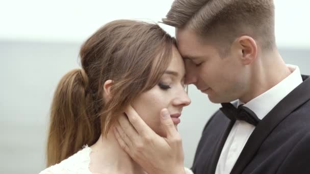 Novio sosteniendo suavemente la mano en la cara de la novia — Vídeo de stock