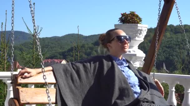 Розслаблена жінка сидить на дерев'яній гойдалці — стокове відео
