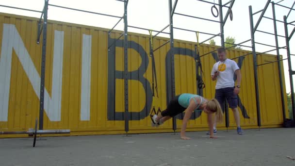 Trainer hilft Mädchen bei Übungen am Boden — Stockvideo