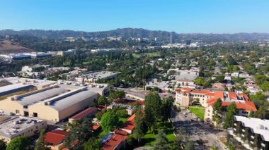 Burbank, Los Angeles, California 'daki Warner Bros Stüdyoları' nın insansız hava aracı görüntüleri. Çevresindeki yerleşim bölgeleri, yeşil parklar ve açık mavi gökyüzünün altındaki uzak Hollywood Tepeleri. Şey...