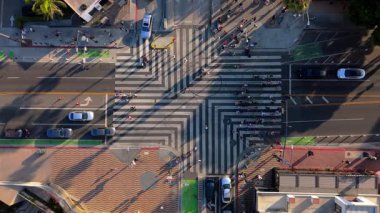 İnsansız hava aracı görüntüleri, güneşli bir öğleden sonra Santa Monica Rıhtımı yakınlarındaki yaya geçidini gösteriyor. Yaya geçidinin çizgili geometrik tasarımı çarpıcı bir tavan yaratır.