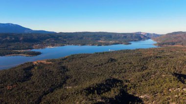 Drone, Güney Kaliforniya 'nın San Bernardino Dağları' ndaki ormanlı tepelerle çevrili Big Bear Gölü 'nün geniş panoramik görüntüsünü yakalar. Manzara sakin mavi suyu, engebeli araziyi ve...