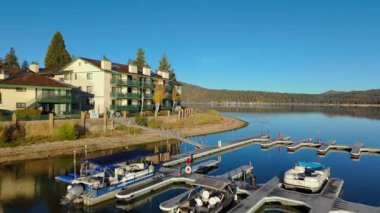 Göl kenarındaki apartmanların balkonları, marina rıhtımları ve Kaliforniya 'daki sakin yansıtıcı suların insansız hava aracı görüntüleri. Kamera sahil boyunca sorunsuzca uçuyor ve konutu gösteriyor.