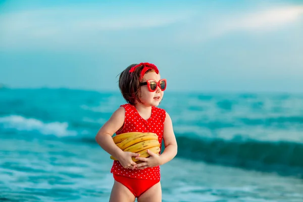 Маленькая Девочка Красном Купальнике Солнцезащитных Очках Стоящая Босиком Пляже Держащая Стоковое Изображение