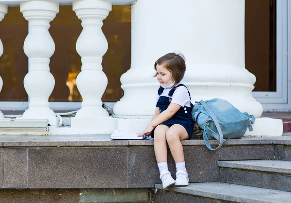 Una Ragazza Uniforme Scolastica Una Maschera Medica Seduta Con Uno — Foto Stock