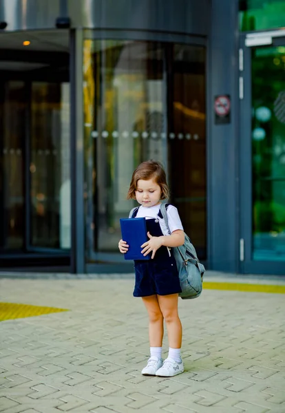 美しい白人の少女が学校の近くに立っていますリュックを手に日記を持っています — ストック写真