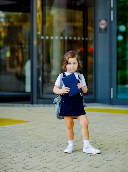 美しい白人の少女が学校の近くに立っていますリュックを手に日記を持っています — ストック写真