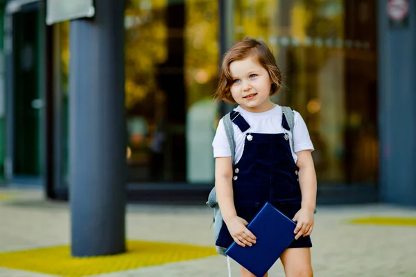 美しい白人の少女が学校の近くに立っていますリュックを手に日記を持っています — ストック写真
