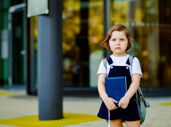 美しい白人の少女が学校の近くに立っていますリュックを手に日記を持っています — ストック写真