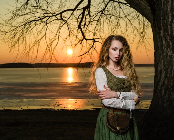 Mujer con el pelo ondulado largo en el vestido histórico en la puesta del sol . —  Fotos de Stock