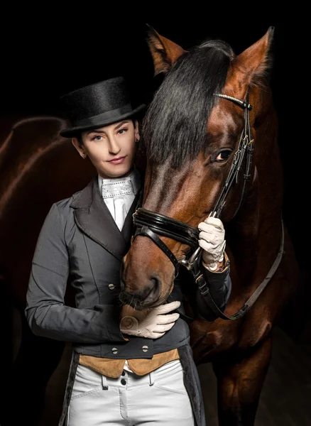 Caballo de uniforme con un caballo marrón en el establo . — Foto de Stock