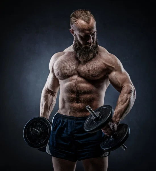 Power athletic bearded man in training pumping up muscles with d — Stock Photo, Image