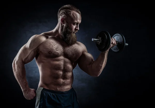 Power athletic bearded man in training pumping up muscles with d — Stock Photo, Image