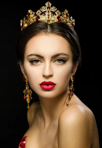 Beautiful girl in a golden crown and earrings on a dark backgrou — Stock Photo, Image