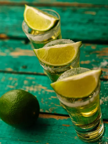 Tequila messicana in oro con lime e sale su tavola di legno — Foto Stock