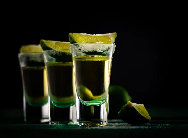 Tequila de oro mexicano con lima y sal sobre mesa de madera — Foto de Stock