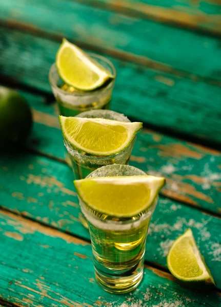 Tequila messicana in oro con lime e sale su tavola di legno — Foto Stock