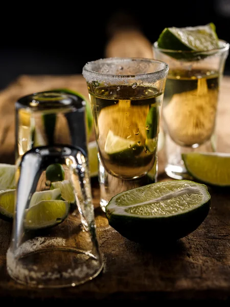 Tequila messicana in oro con lime e sale su tavola di legno — Foto Stock