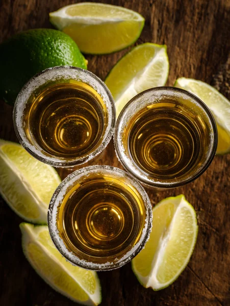 Gold tequila shot with lime on wooden background — Stock Photo, Image