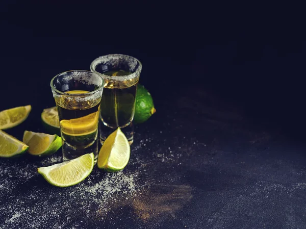 Mexikanischer Gold-Tequila mit Limette und Salz auf dunklem Tisch. — Stockfoto