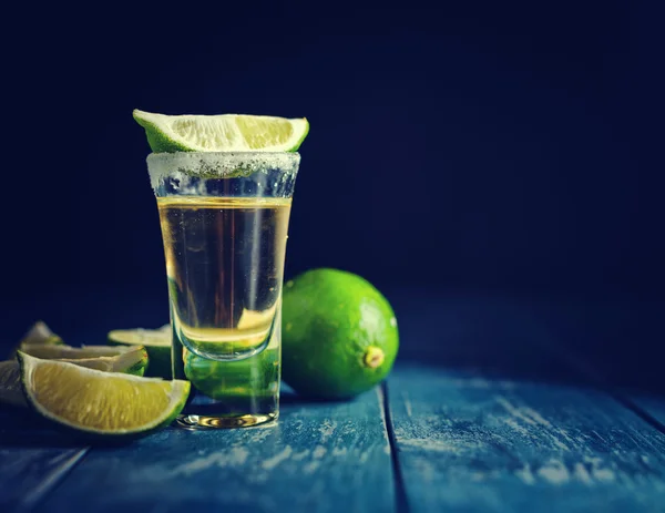 Tequila messicana in oro con lime e sale su tavola di legno — Foto Stock