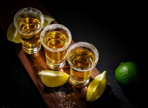Tequila de ouro mexicano com limão e sal na mesa de madeira — Fotografia de Stock