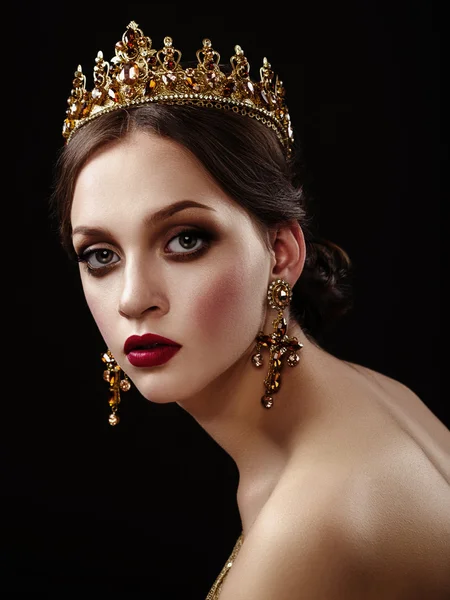 Beautiful brunette girl with a golden crown, earrings and profes — Stock Photo, Image