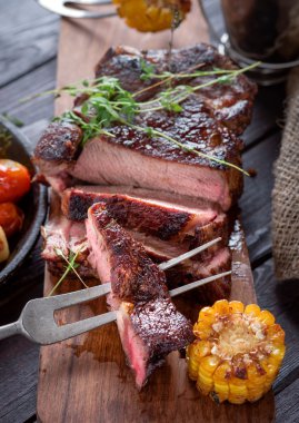 Bir kesme tahtası üzerinde ızgara biftek dilimlenmiş.