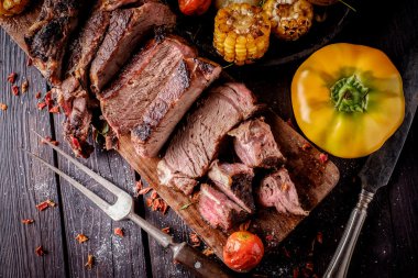 Bir kesme tahtası üzerinde ızgara biftek dilimlenmiş.