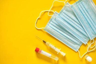 Sarı arka planda tıbbi koruyucu maske ve şırınga. Küresel aşı. Aşı Coronavirus 'a karşı savaş kavramı.