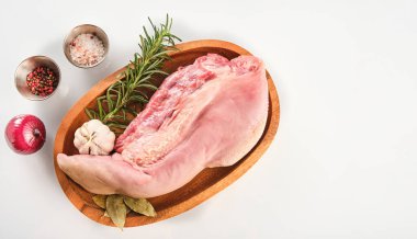 Raw cow tongue with greenery, garlic and dry peppers, close up, top view, high angle, white background