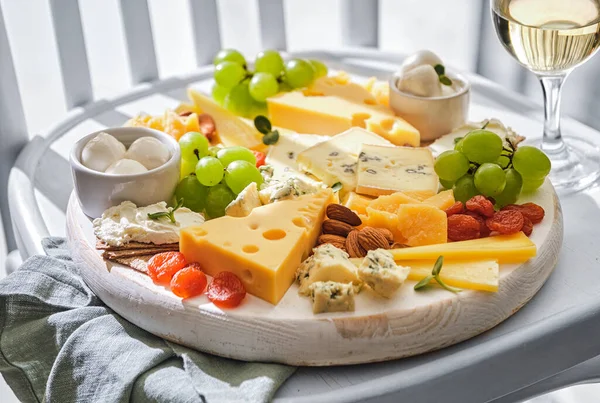 白い背景にフルーツと白ワインのガラスとチーズプレート 木の板の上で異なるチーズ チーズセット — ストック写真