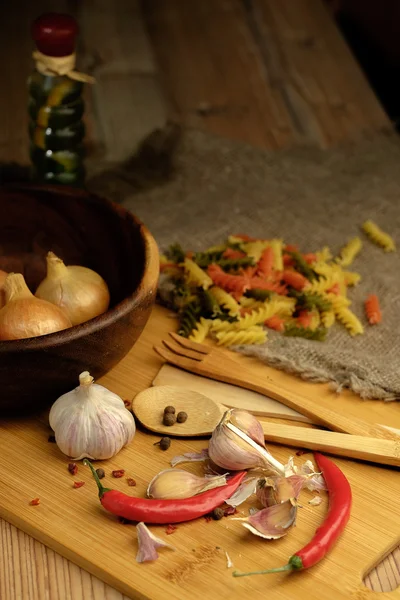 Spaghetti, Onions and garlic and on a wooden table. — Stock Photo, Image