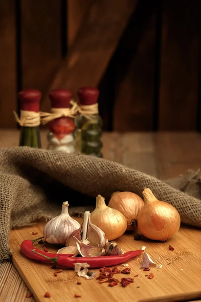 Chili pepper, onion and garlic on a wooden cutting board. — Stock Photo, Image